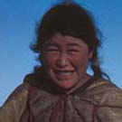 Photograph of an Inuit woman standing in the snow with a group of dogs, Arviat (formerly Eskimo Point), Nunavut, 1936