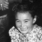 Photograph of a group of Inuit children who are sitting on the floor laughing and playing, unknown location, Nunavut, circa 1955